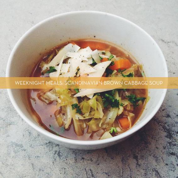 Cabbage soup with vegetables in large bowl on table.