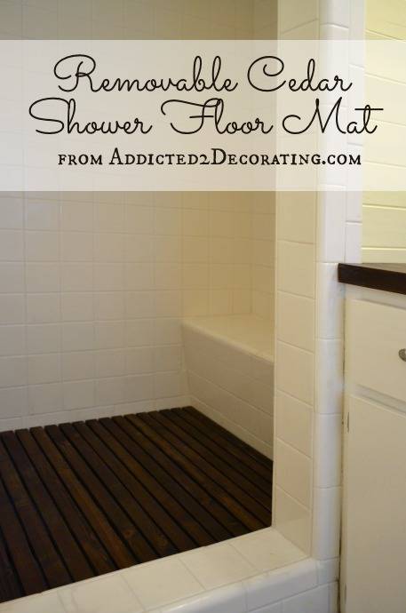 A shower area has a black floor mat.