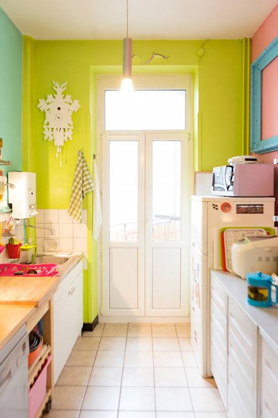 A kitchen has a white tiled floor and lime green walls.