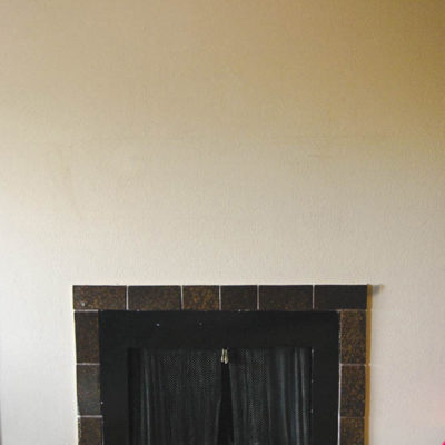 A black fireplace sits undecorated on a white wall.