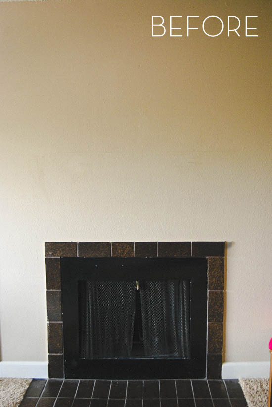 A black fireplace sits undecorated on a white wall.