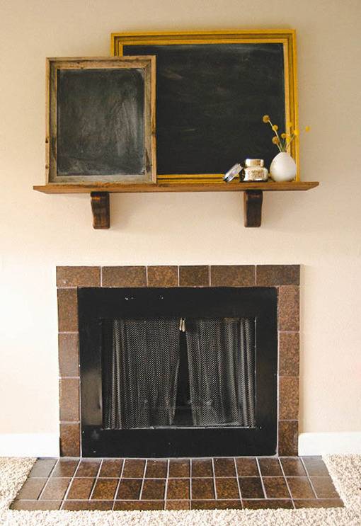 Two black chalk boards in gold frame sit on the shelf above a fireplace.