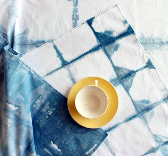 A cup of tea resting on a dish over a patterned surface or material.