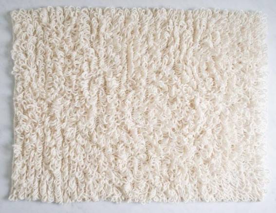 A piece of white carpet is cut out into a rectangle.