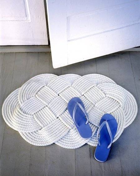A blue pair of flip-flops it's on a white swirling rug made of rope.