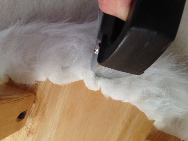 Soft cushioning being stapled onto wood frame.