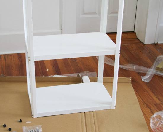 A white organizing shelf sits on a flattened cardboard box.