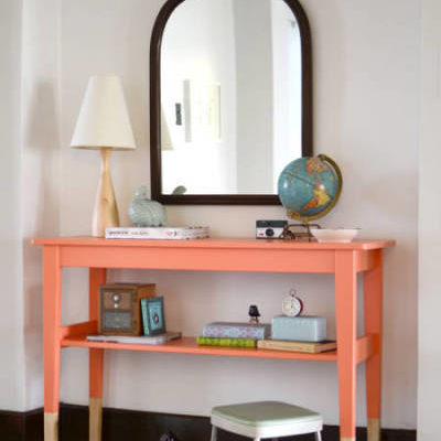 A rounded mirror sits behind a short table with a globe and lamp on the ends.