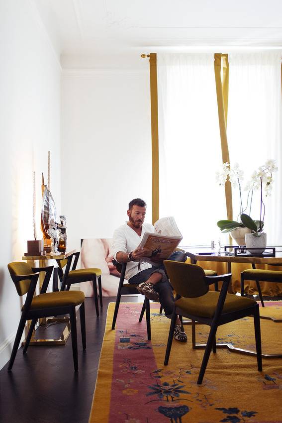 A man is sitting in a chair reading a newspaper.