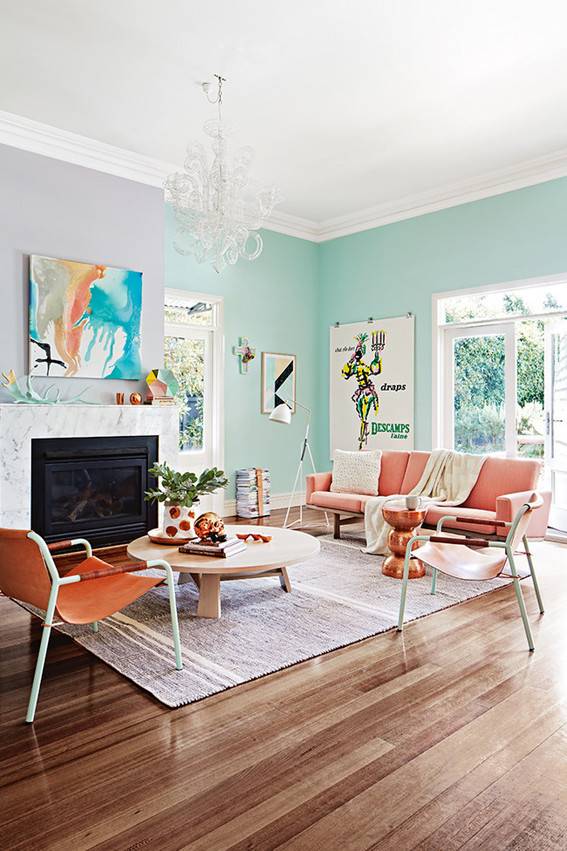 A living room has wooden floors, orange chairs and light blue walls.