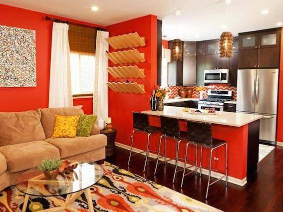 Three black stools sit under a counter in a red and black living and cooking space.