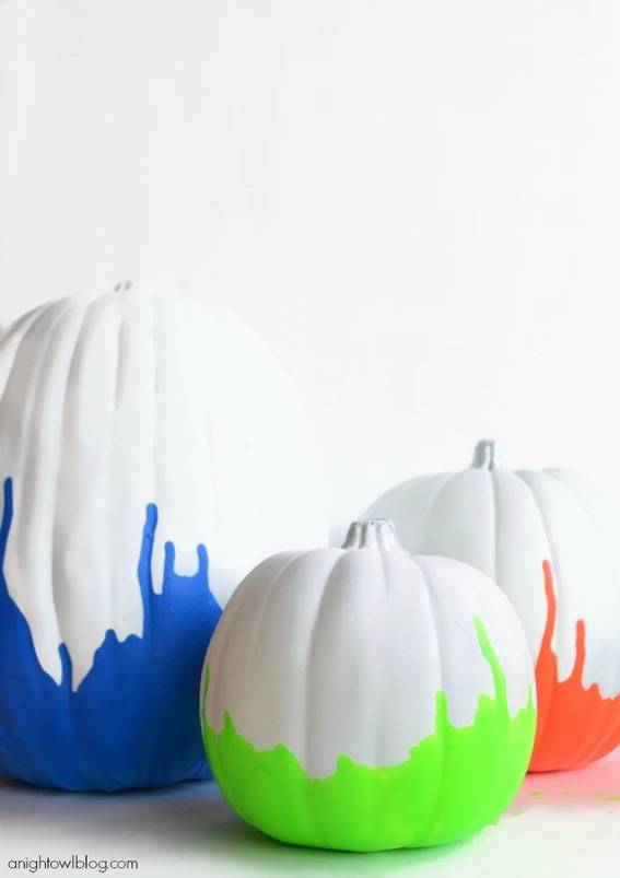 Trio of pumpkins painted in white with blue, green, and orange paint on bottoms.