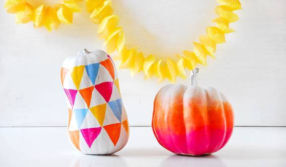 Two colorful mini pumpkins and a yellow decorative object in the background