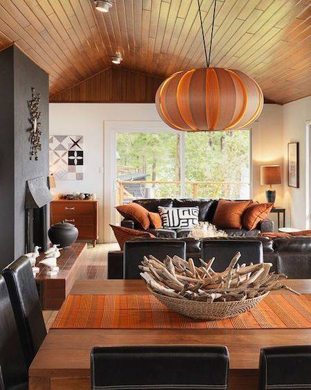 A table has a large orange bowl shaped lamp above it.