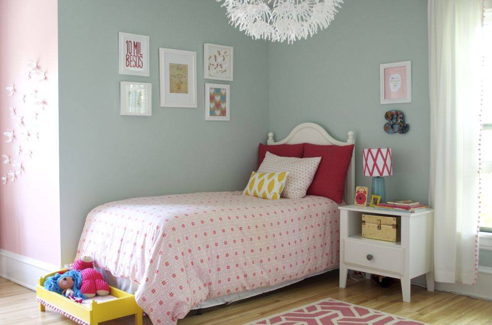 Kid's bed along with pillow, dolls, mini cabinet and photo frames on the wall.