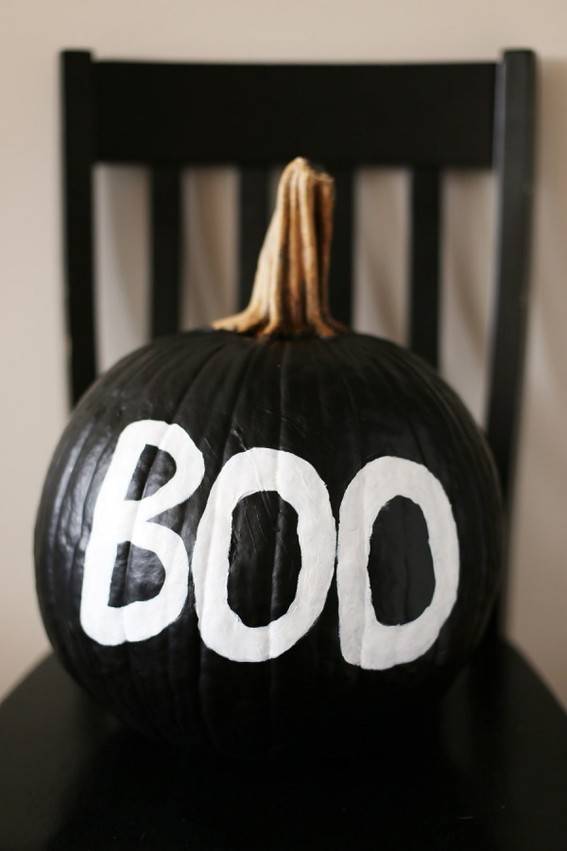 A black pumpkin has the word Book written on it in white.