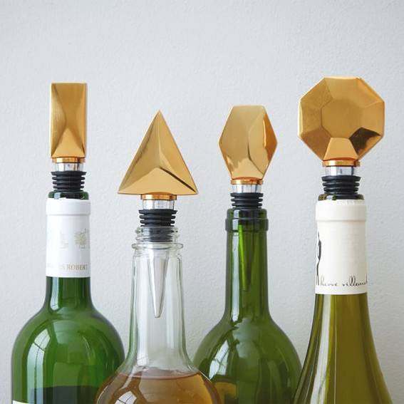 Four wine bottles in a row have oddly shaped corks on them.