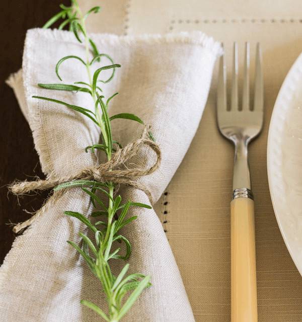 A fork sits near a napkin with a green fern on it.