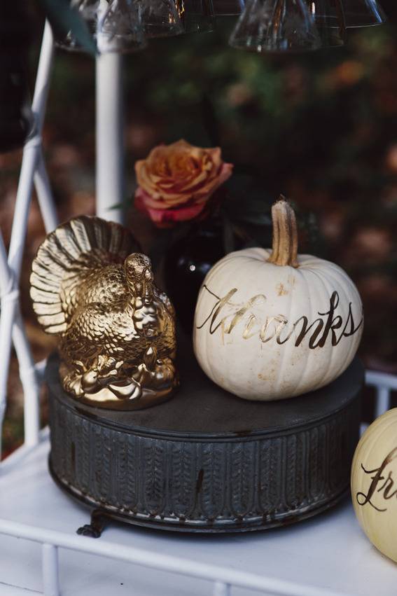 Golden turkey statue and white pumpkin with word thanks embossed in gold on black pedestal.