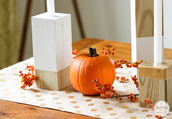 Cubical wooden columns with pumpkin on table with dotted table runner and sprays of berries.