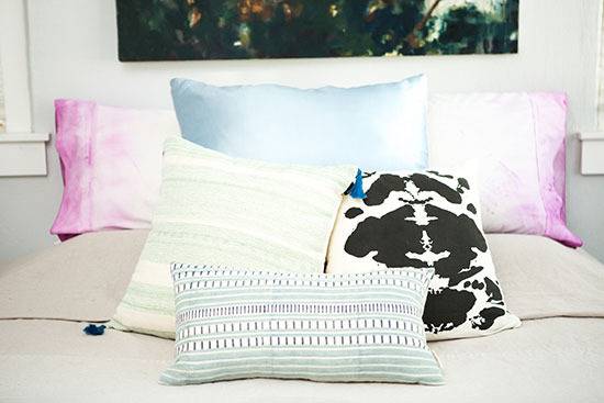 Pillows are sitting on a bed with a picture hanging over it.