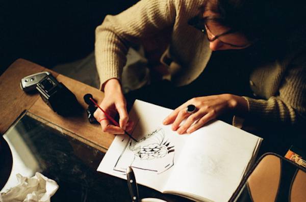 A person is drawing on paper in a dark lit room.