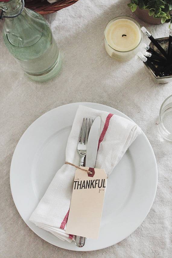 Flatware in a napkin on a plate on a white tablecloth.