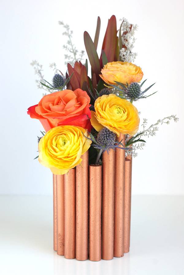 Colorful roses are placed in copper flower vase.