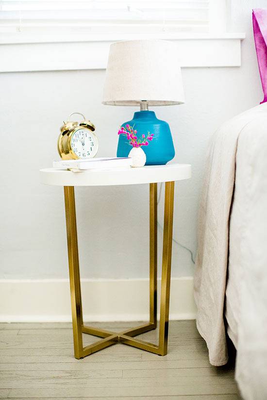 "Lampl and clock is on the table beside bed."