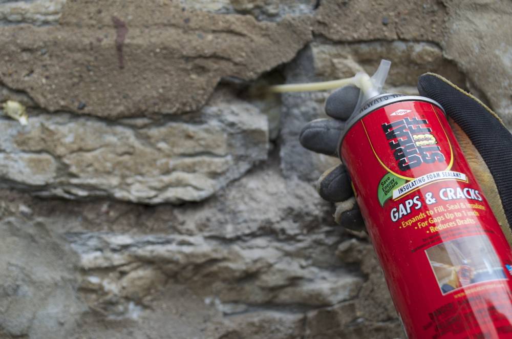 A can of sealer spraying a brick wall.