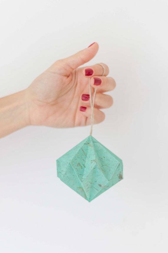 Hand holding a small, blue paper lantern ornament.