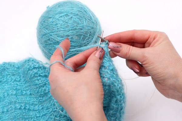 A person is working with light blue yarn.