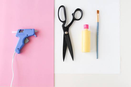 Scissors and other craft tools are set on pink and white backgrounds.