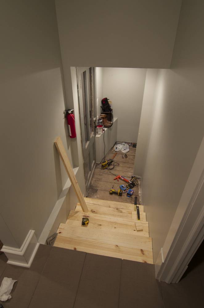 Wooden staircase in an entryway near construction tools.