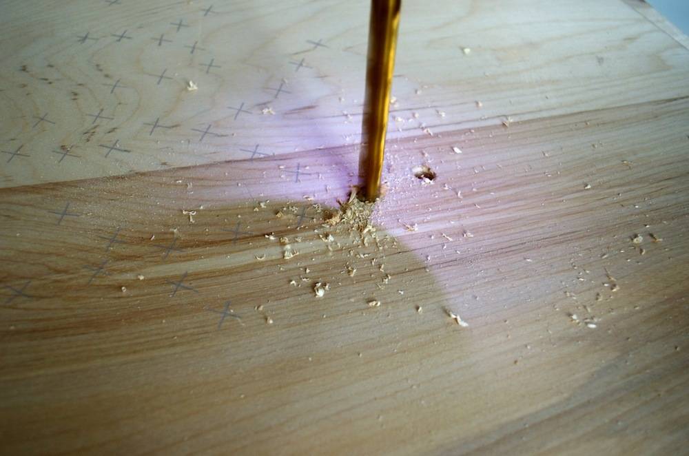 A wood floor has a bar being drilled into it.