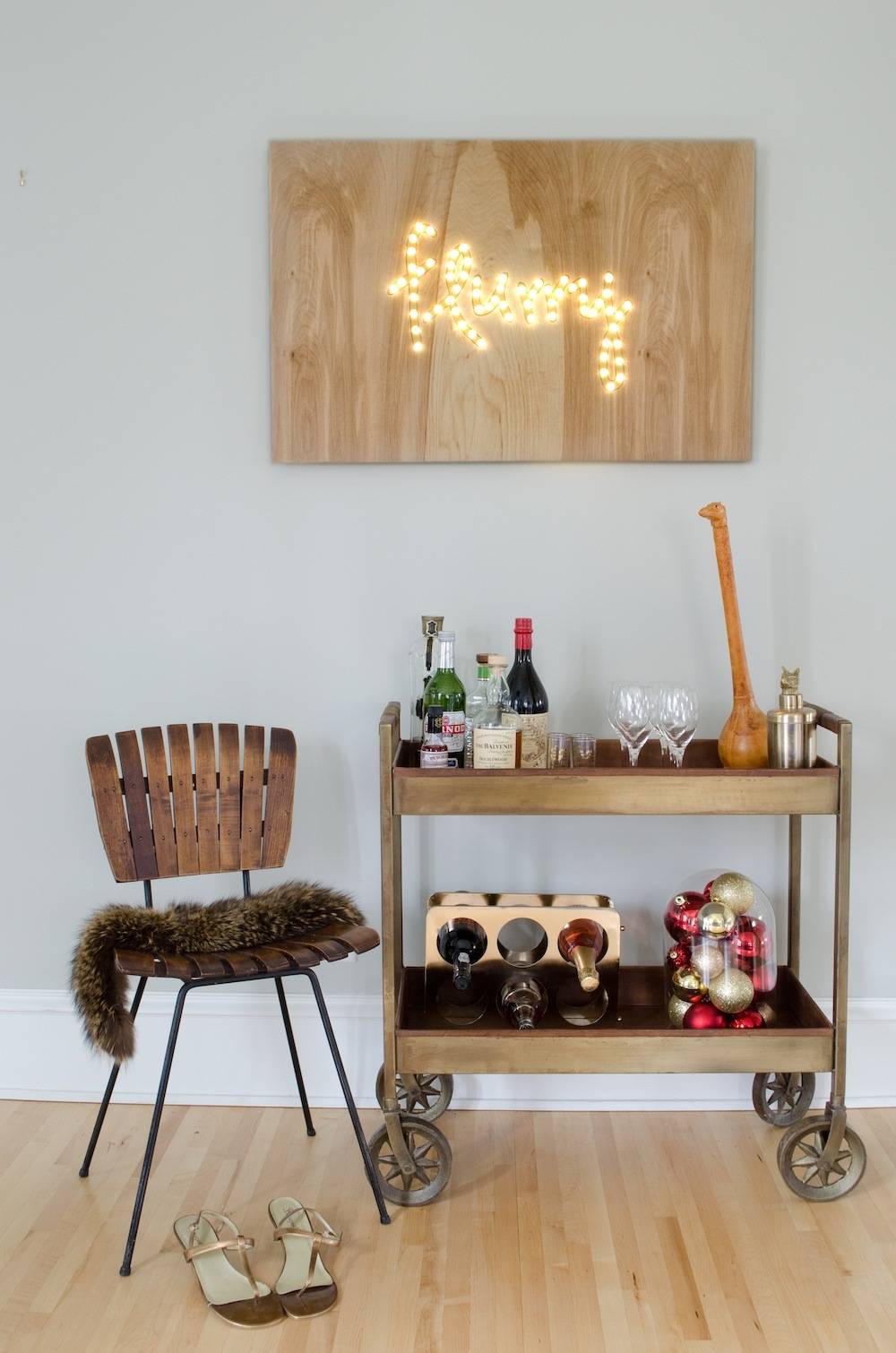 Metal rolling tray with wine bottles and decorations near wooden chair with metal legs.