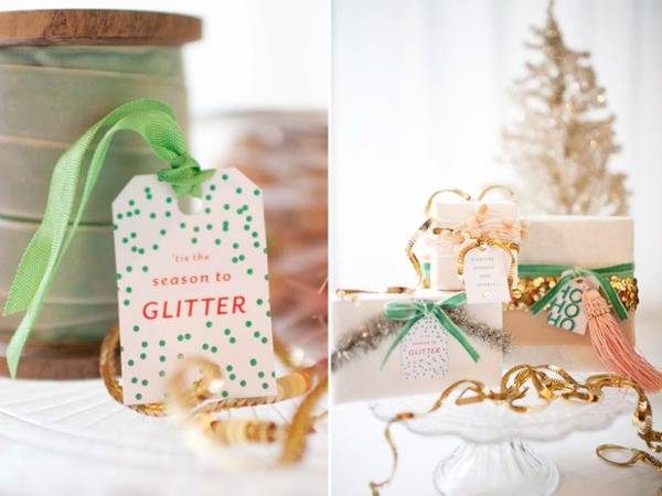 Group of gifts wrapped with hand made ribbons and tags near white Christmas tree.