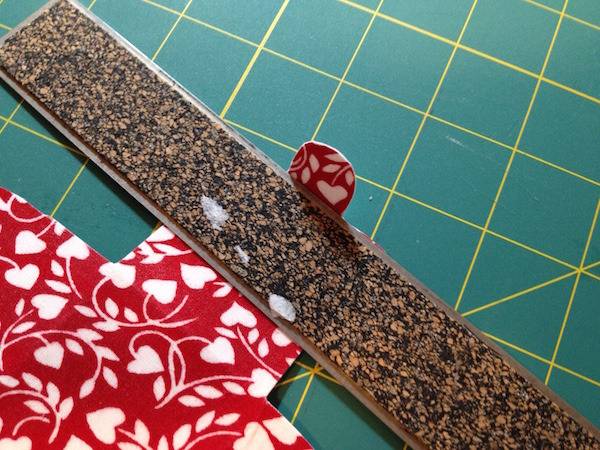 The back of a ruler on top of red and white designed fabric.
