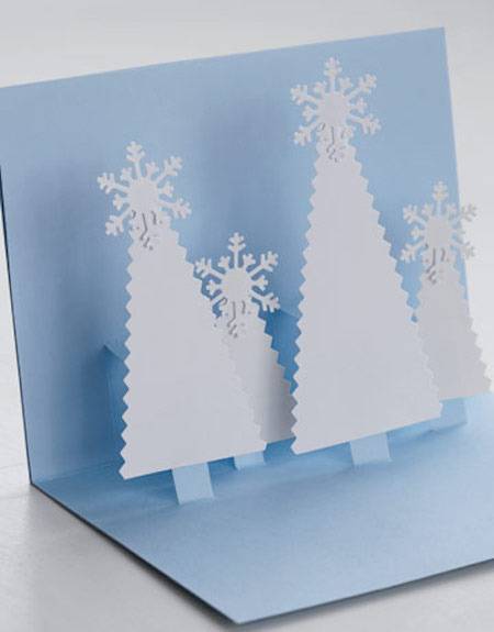 A blue card with white pop up trees lies open.