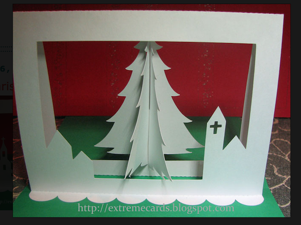A white Christmas tree cutout is placed near a red background.