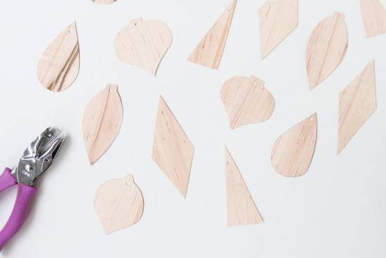 Painted veneer ornaments on a white table next to a hole puncher with a purple handle.