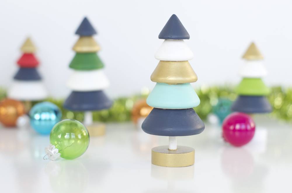 Colorful toy Christmas trees are sitting on a white surface.