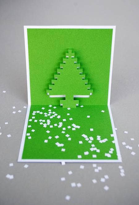 A folded Christmas card with a paper Christmas tree in it.