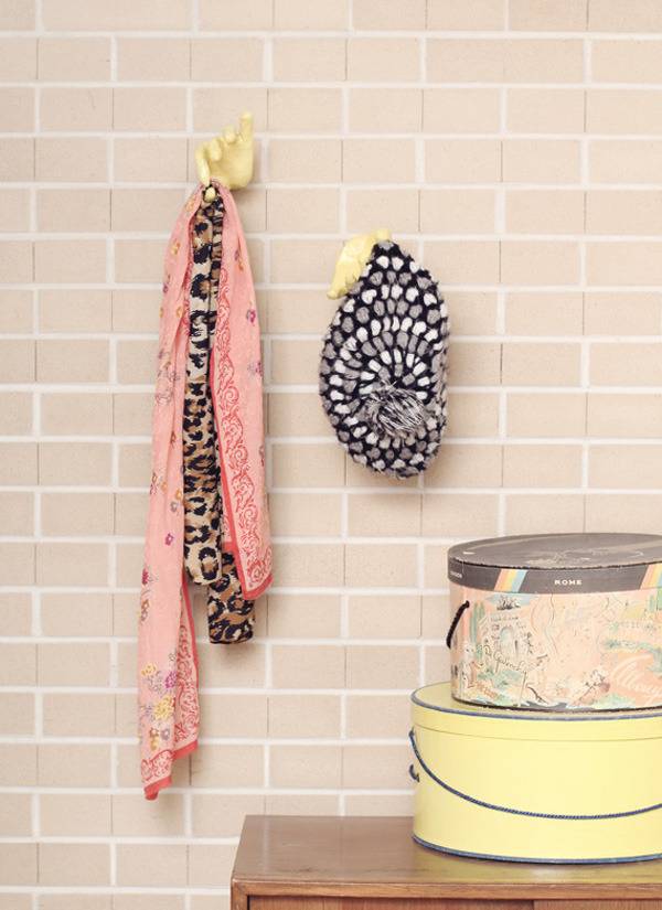 Items are hanging on hooks on a pink brick wall.