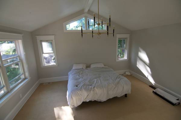 Bedroom with white walls, white sheets, white pillows and wooden floor.