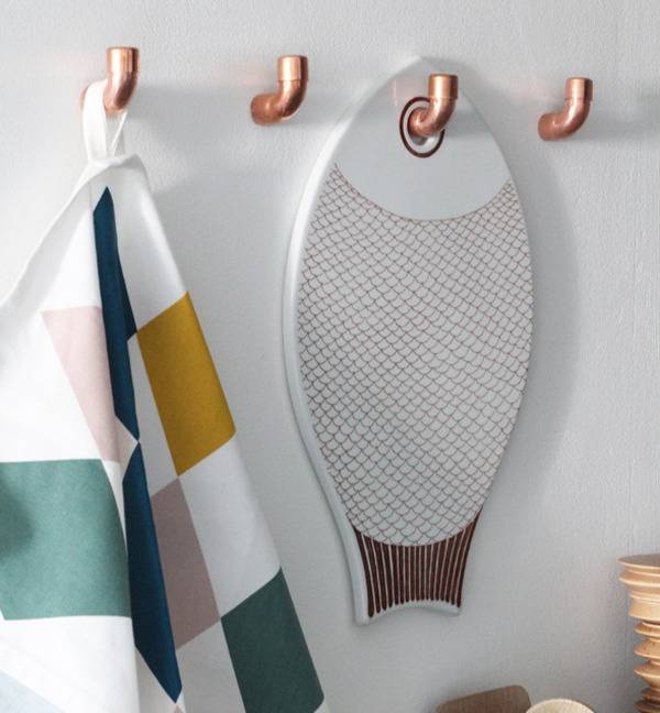 Metal hooks on the white wall hold objects.
