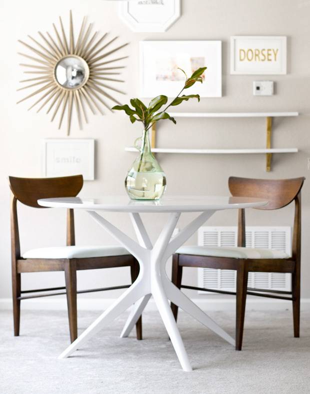 A star leg shaped white plastic mid-century modern table has two mid-century modern wood chairs.