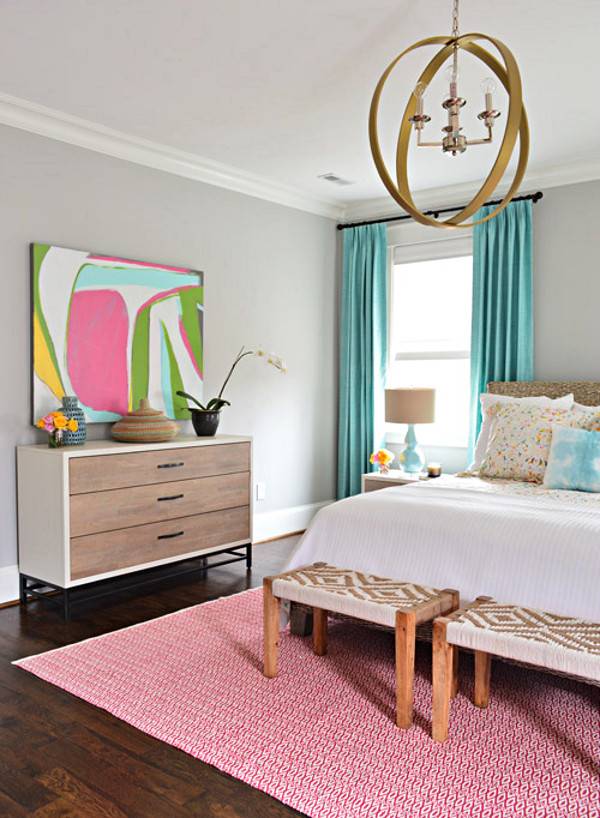 Pink color bedroom with wall art frame, cabinet, table lamp, bed, and shandler.