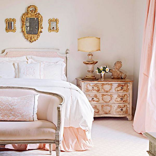 A large bed with white bedsheets next to a pink nightstand and pink curtains.