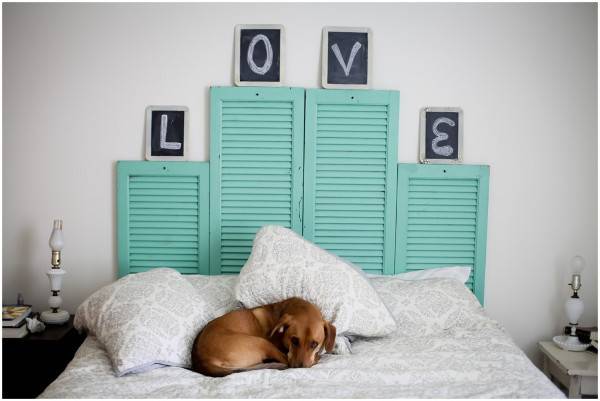 Dog is sleeping on the white bed and headboard decorated with love wall frames.